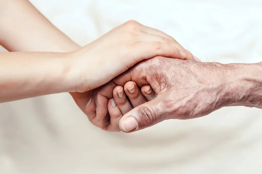 Junge Hand hält ältere Hand, beide Hände eng umschlossen.