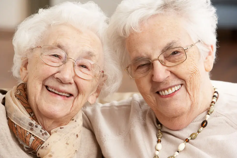 Foto von zwei älteren lächelnden Frauen mit weißen Haaren.